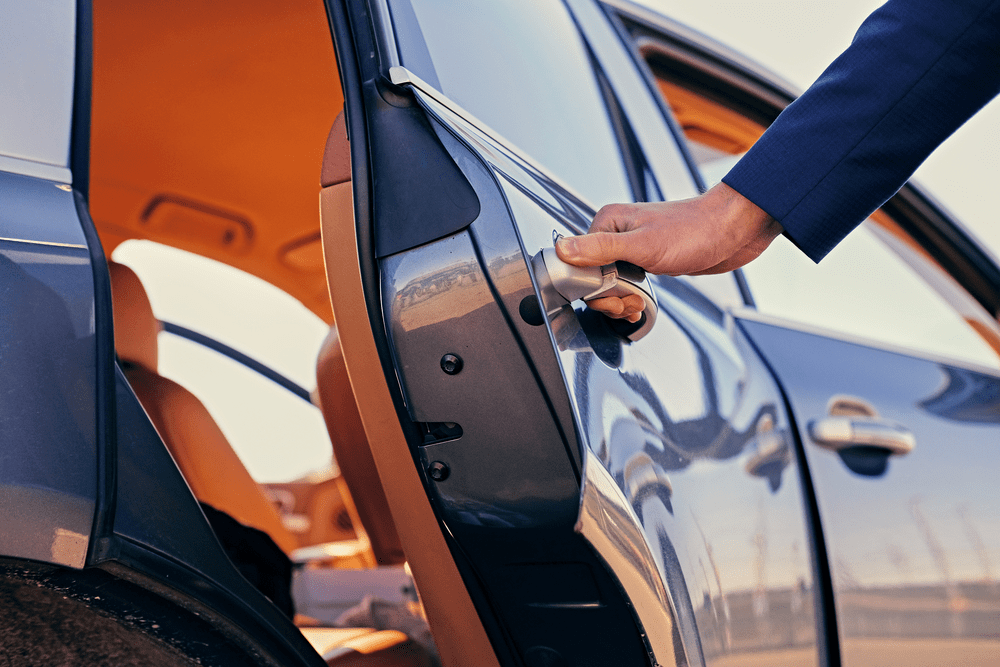 Chauffeur opening the door of a luxury car, showcasing premium service and attention to detail for executive clients.